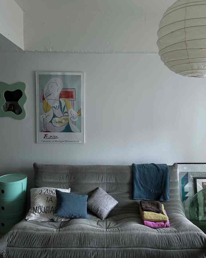 グレー調のリビング、中央にグレーのトーゴソファとカラフルなブランケットが置かれた、清潔でナチュラルな雰囲気の空間