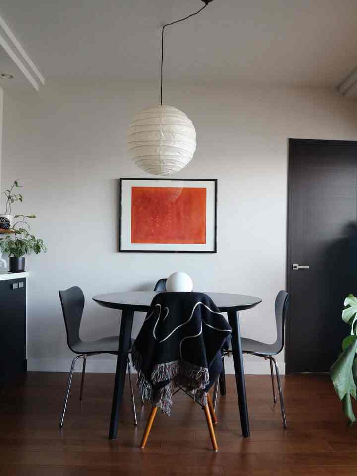 A clean mid-century modern dining room with white walls and wood-tone floors, featuring a round table and chairs