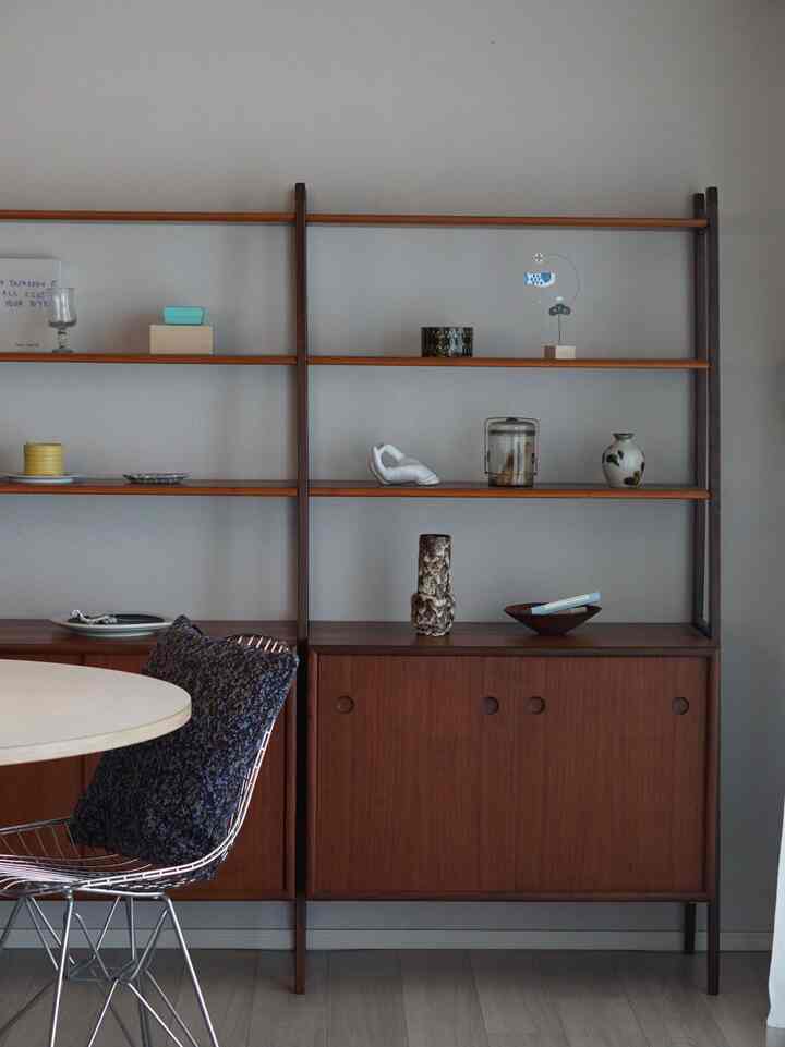 Wood tone natural Nordic vintage dining room featuring vintage shelves and a simple dining table with wire chair