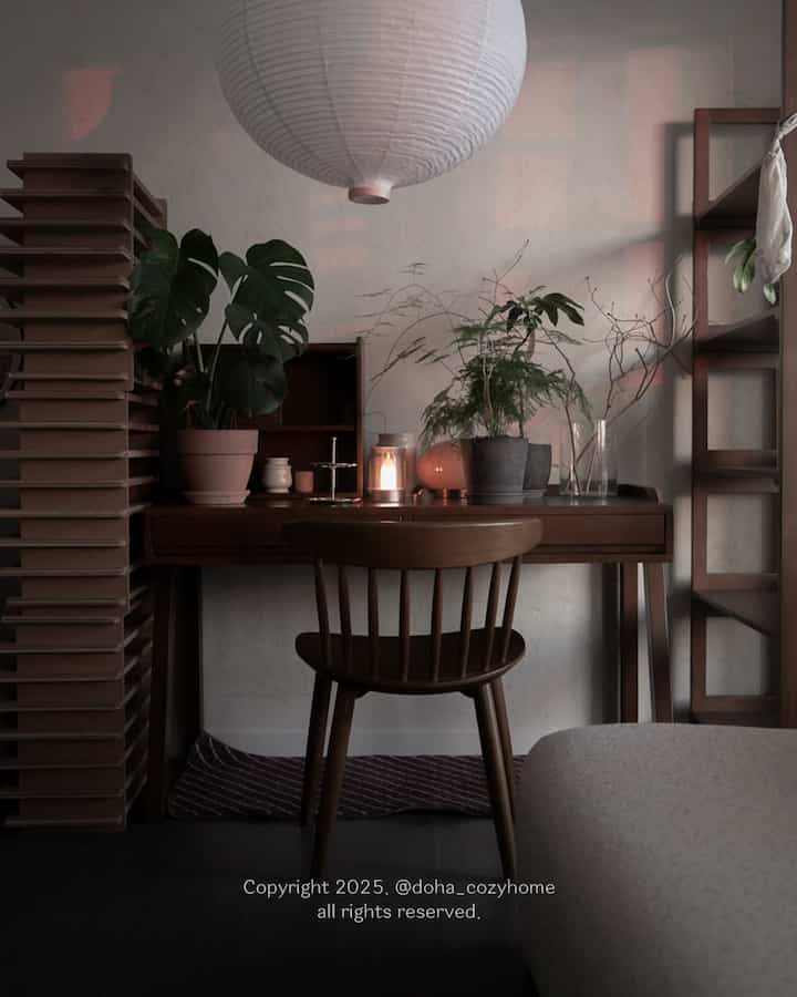 Cozy study corner featuring warm wood tone furniture and lush plants with soft lighting ambiance