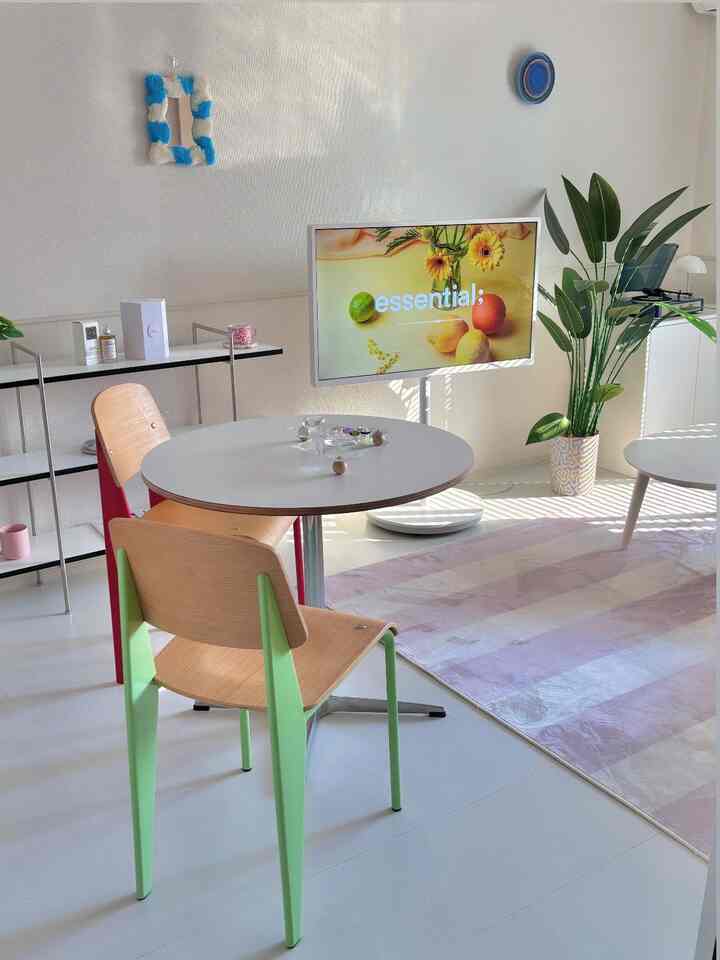 明るいホワイトとパステルカラーのカフェ風リビング、丸テーブルにカラフルな椅子が配置された雰囲気のあるインテリア