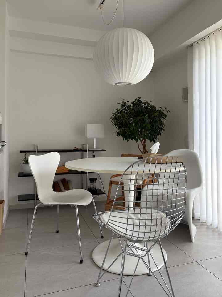 White and gray toned dining room featuring a round dining table, assorted chairs, pendant light, and vertical blinds creating a clean look