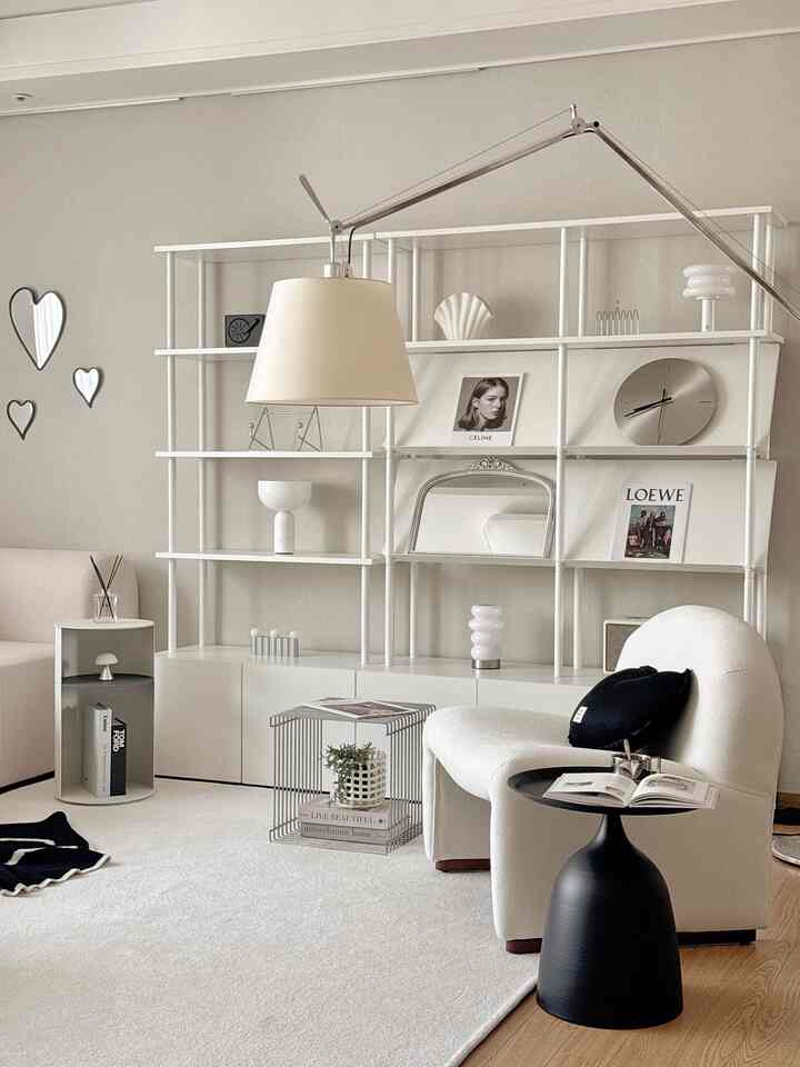 ホワイトとモダンな色調のリビング、曲線的なソファと黒のサイドテーブル、大きな白い棚が配置された印象的な空間