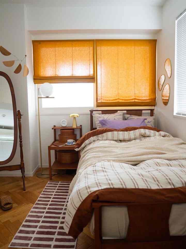 Warm-toned bedroom featuring orange window shades and wooden furniture creating a cozy atmosphere