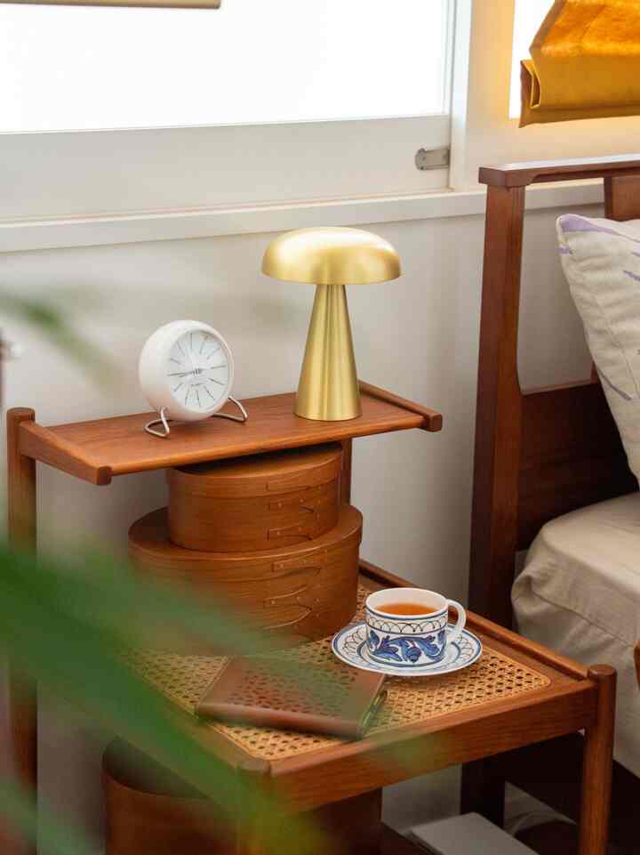 茶色い木製家具とゴールドの照明が調和した、居心地の良い寝室のナイトテーブルスペース