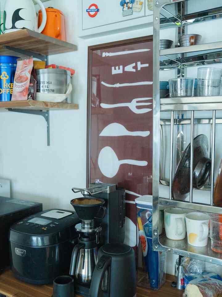 ウッドトーンと黒を基調としたキッチンの一角、コーヒーマシンと電気ケトルが配置された雰囲気のあるおうちカフェスペース