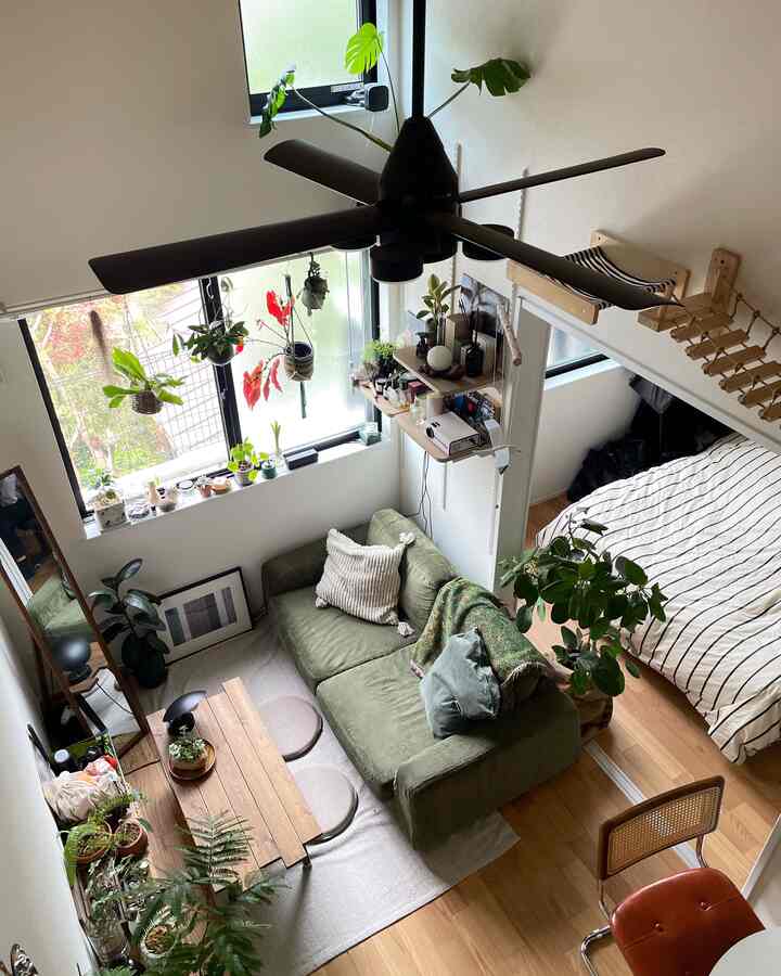 ナチュラルな木目調とグリーンの色合いがあるロフトから見た、居心地の良い一人暮らしのリビングと寝室の空間