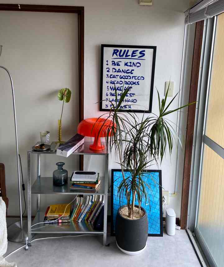 明るいオレンジのテーブルランプと大きな観葉植物が配置されたミッドセンチュリーモダンのリビング空間