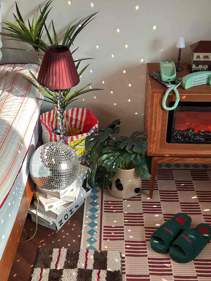 ブラウンの木製家具とレッドのアクセントラグ、自然な植物が配置された居心地の良い寝室のインテリア