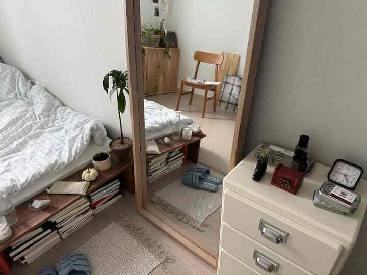 白と木目調の6畳寝室、全身鏡とチェスト、快適なベッドが配置されたシンプルでナチュラルなインテリア