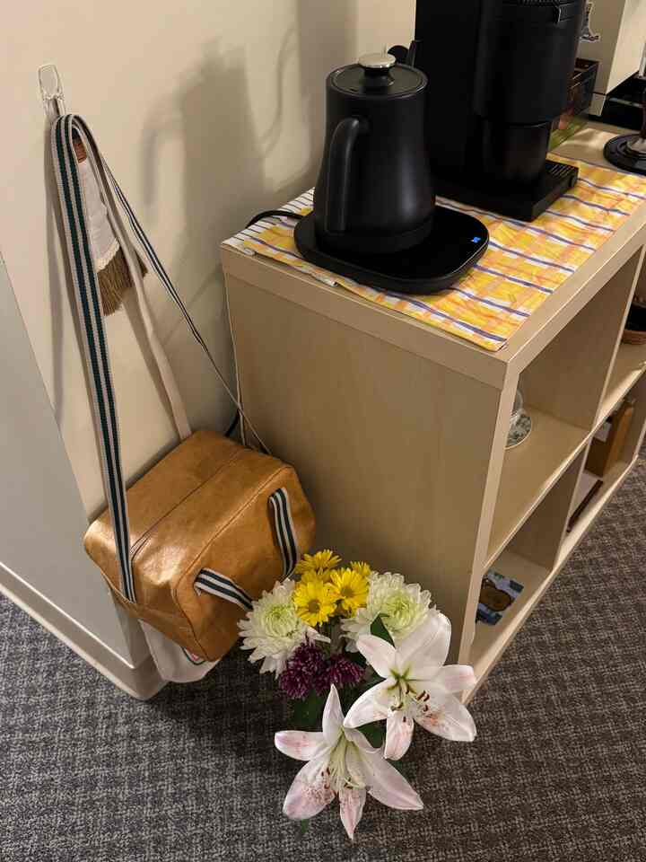 White and yellow toned kitchen space featuring coffee equipment and a flower vase with a cozy, natural home cafe atmosphere