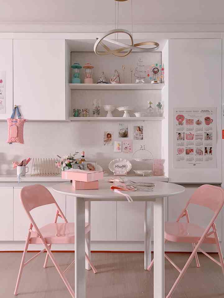 白とピンクの色調のダイニングルーム、丸テーブルと皿・カトラリーが配置された雰囲気のあるおうちカフェ
