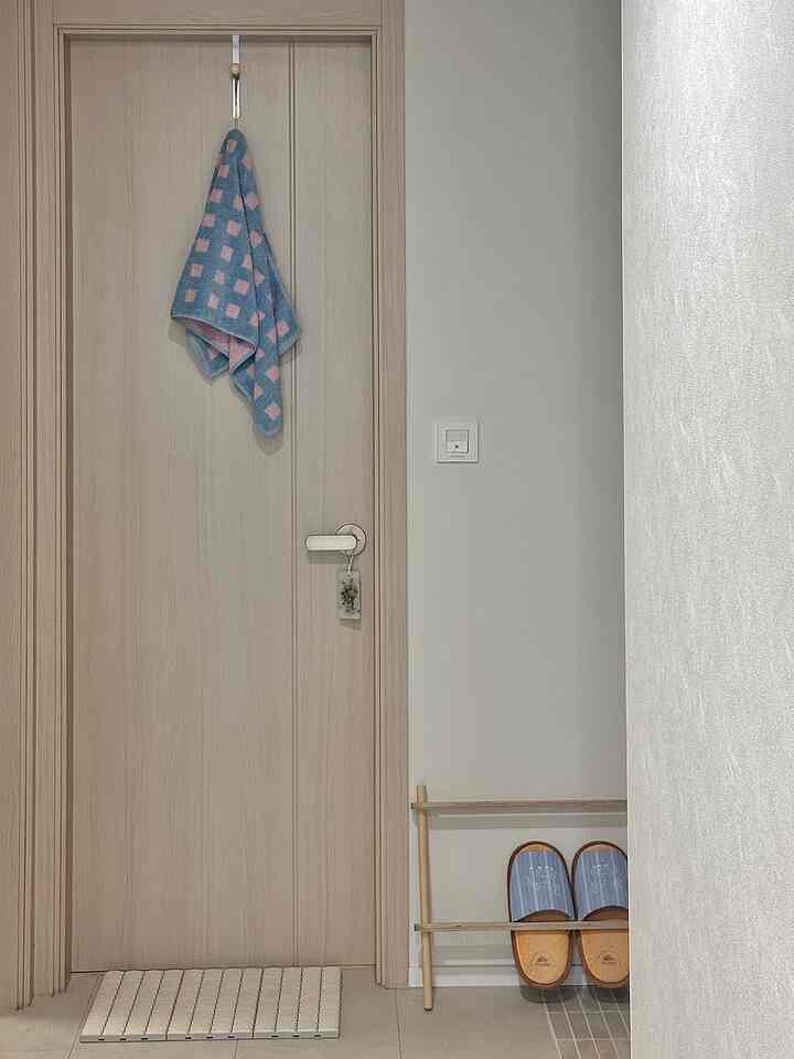 ナチュラルカラーとホワイトのトイレ前、スリッパスタンドとモジュール式バスマットが配置された落ち着いた空間