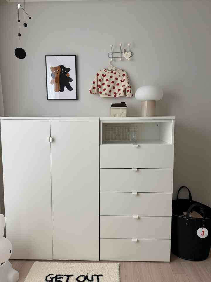 明るいホワイトトーンの子供部屋、シンプルな収納とイチゴ柄の子供服が印象的なミニマルなインテリア