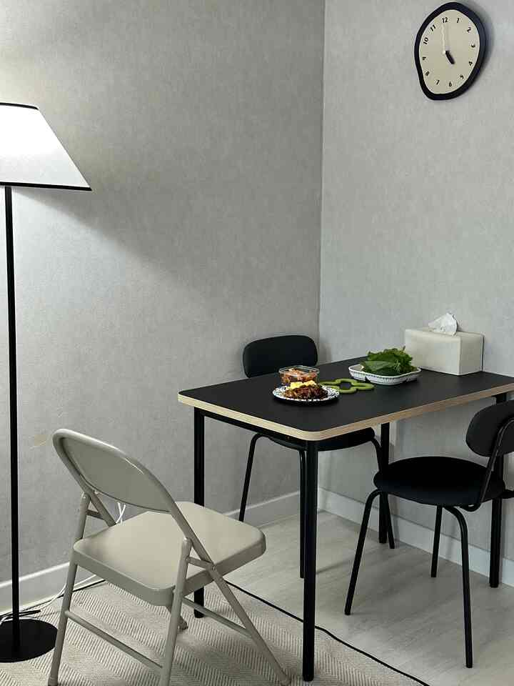 Beige-walled and floored compact kitchen-living space featuring a black dining table with three chairs