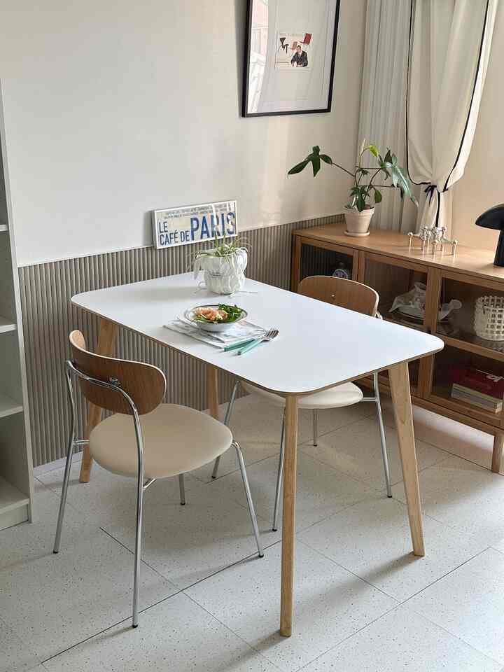 白と茶色のトーンのダイニングルーム、木製のダイニングテーブルと椅子、サイドボードが配置されたシンプルで自然な雰囲気のあるインテリア