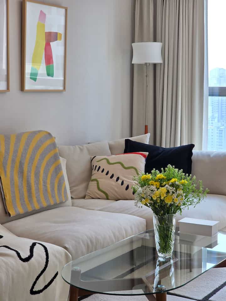 クリームとホワイトのトーンのリビング、広いソファと花瓶が配置された自然で明るい雰囲気のインテリア