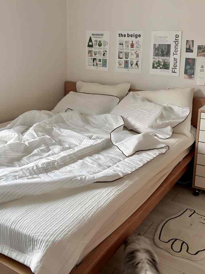 白と木目調の調和がとれた寝室、快適なベッドと壁のポスターが配置されたモダンな雰囲気のインテリア