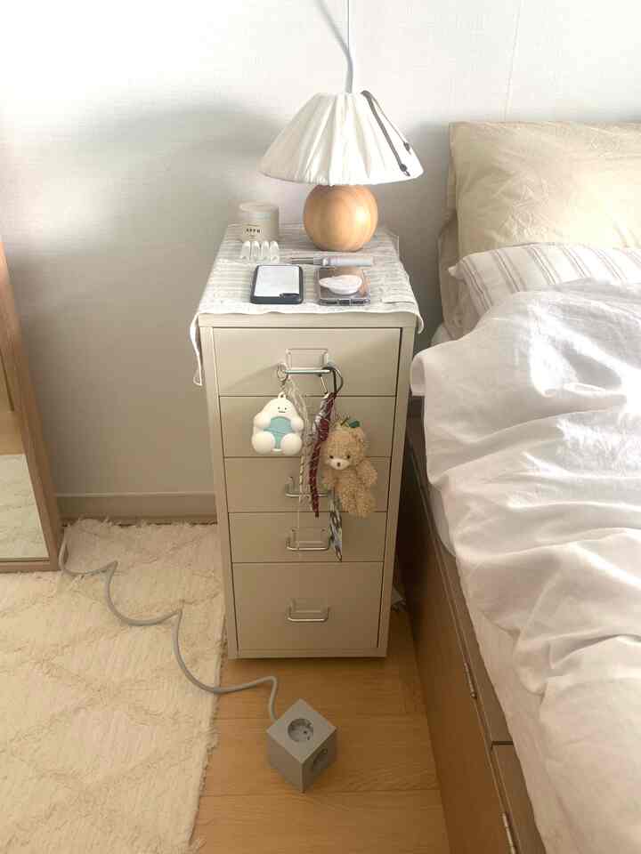 明るいホワイトとウッドトーンが調和したワンルームの寝室、ドレッサーナイトテーブルとベッドが配置された落ち着いた空間