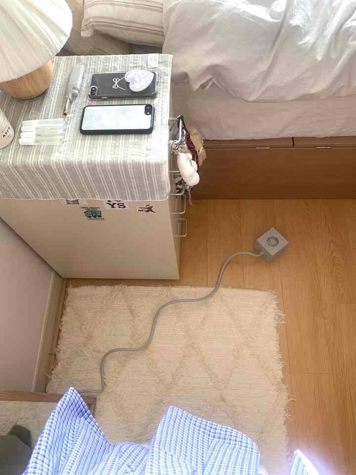 ホワイトと木目調の寝室、ナイトテーブルと収納家具が配置された落ち着いた小さな空間