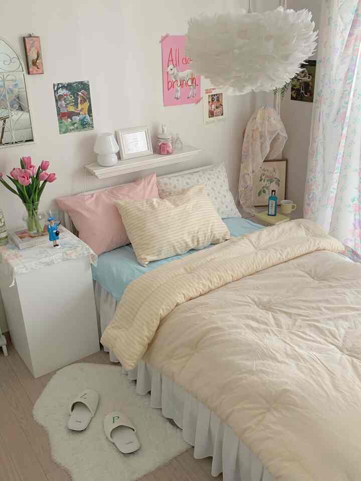 ホワイトとパステル調の寝室、柔らかいピンクとベージュの寝具が配置された雰囲気のある小さな部屋のインテリア