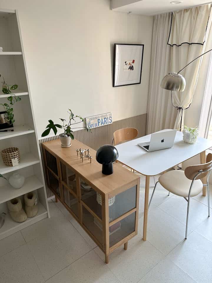 White and wood-toned study-style home office space featuring a sideboard and simple desk creating natural space separation