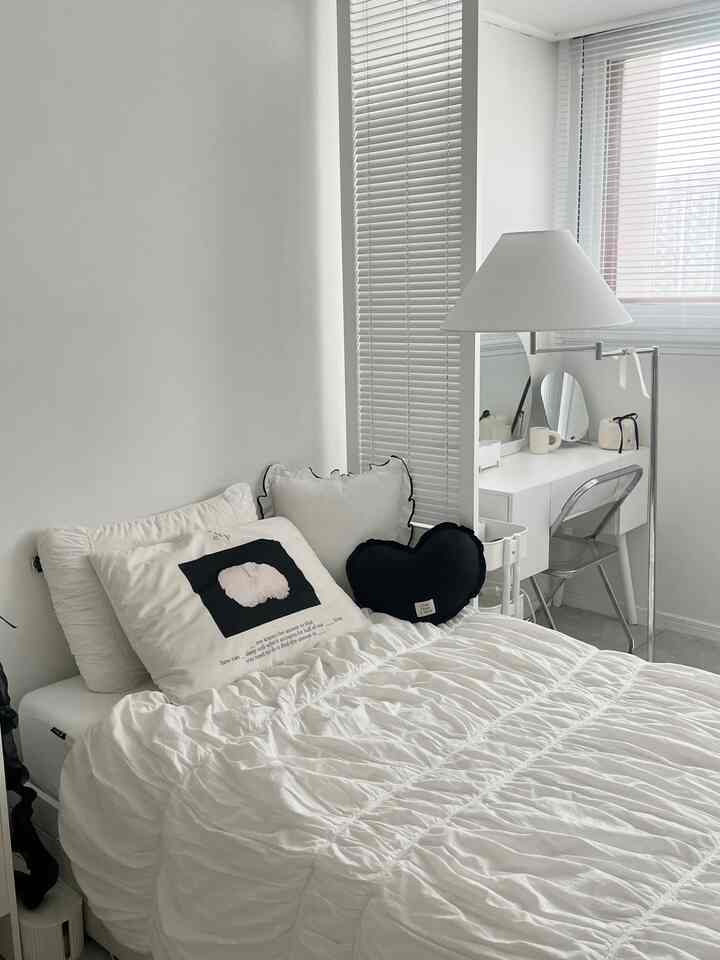 白色調の寝室、中央左にベッド、右に化粧台が配置されたシンプルなインテリア