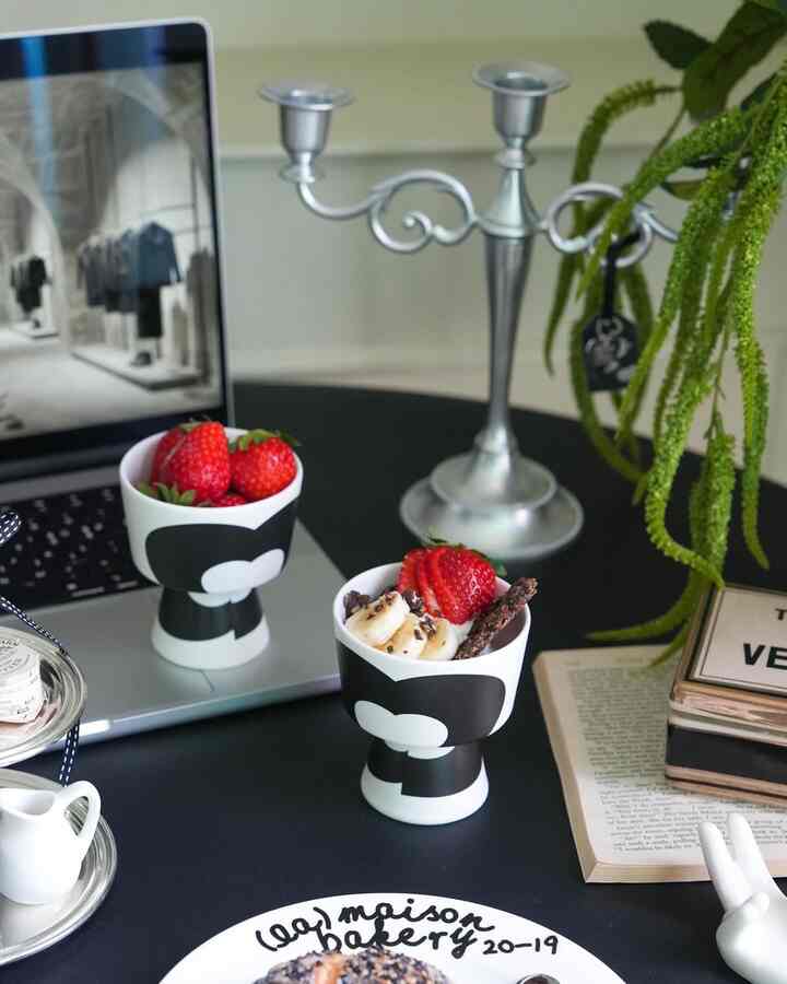 Black table featuring a laptop and bakery plates with strawberries, creating a home cafe and home office vibe
