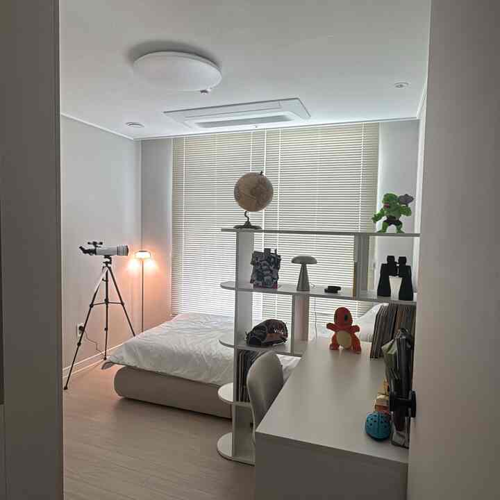 白とベージュの色調の狭い寝室、ベッドとデスクが配置された印象的な空間