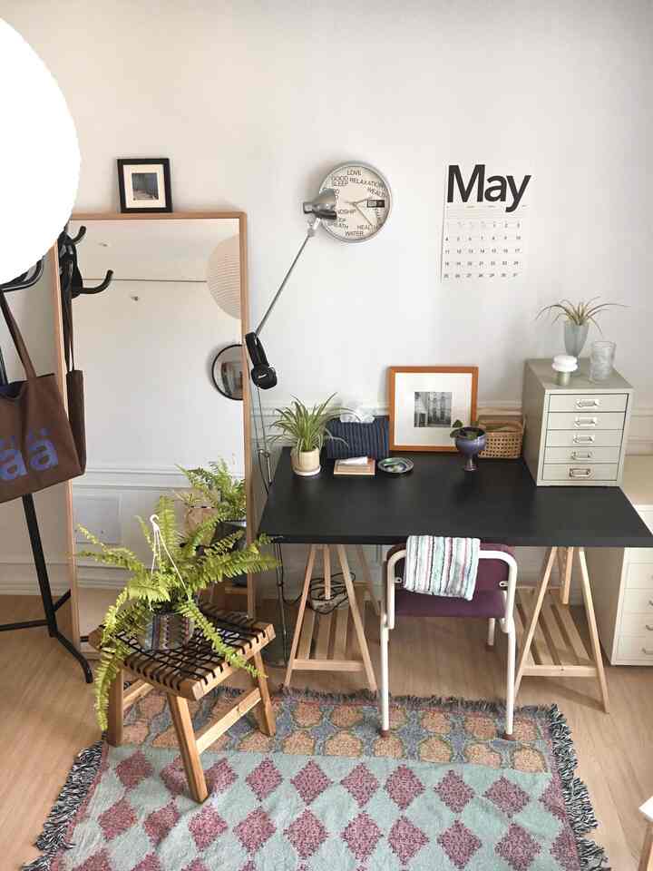 木目調と白壁が調和した北欧スタイルのホームオフィス、黒いデスクと多様な植物が配置された雰囲気のあるインテリア