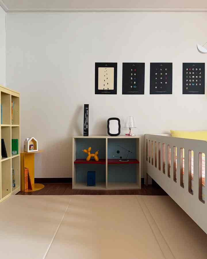 白とベージュの色調の子供部屋、子供用ベッド、本棚、ナイトテーブル、教育用ポスターが配置されたモダンなインテリア