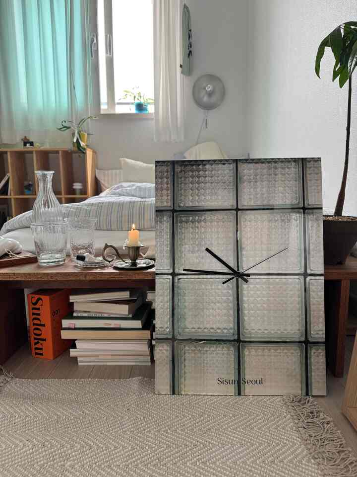 ホワイトと木目調が調和した一人暮らしの寝室、小さなテーブルと本棚が配置されたシンプルで落ち着いたインテリア