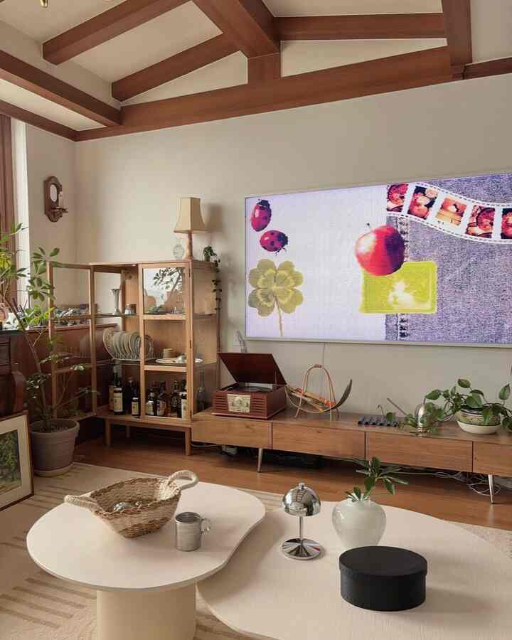 ウッドトーンとホワイトのリビング、ヴィンテージ小物と大型テレビが配置された暖かくシンプルな空間