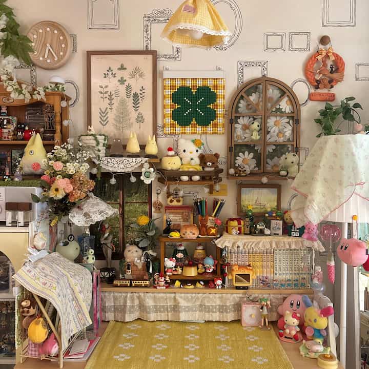 黄色とナチュラルな色調の田舎風の部屋、デスクと棚にジブリのフィギュアやグッズがかわいらしく配置された印象的な空間