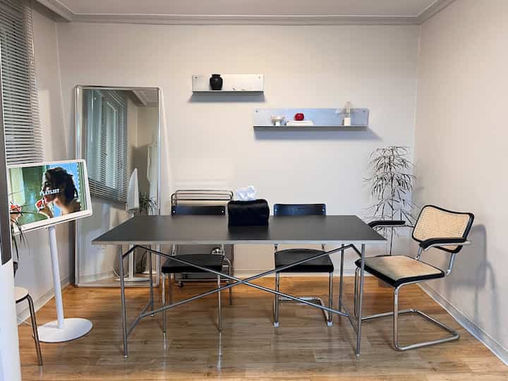 Natural modern dining room featuring a black dining table and chairs centered, wood-tone floor and white walls creating a harmonious space