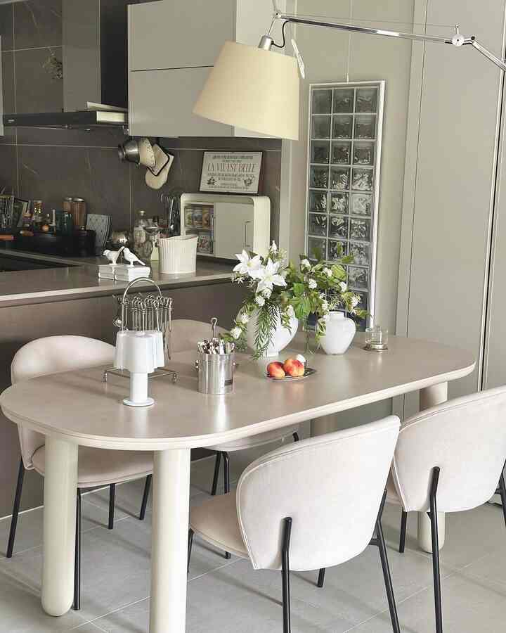 ナチュラルカラーのキッチン、ベージュのダイニングテーブルと椅子が配置され、フロアランプが柔らかい光を演出する雰囲気のあるインテリア