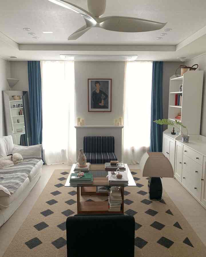 白と青のトーンのリビング、広いソファとパターンラグが配置された清潔感のある空間