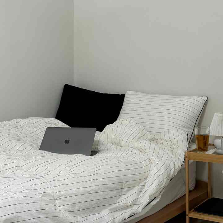 White and black bedroom space featuring a bed with striped bedding in a clean, modern setup