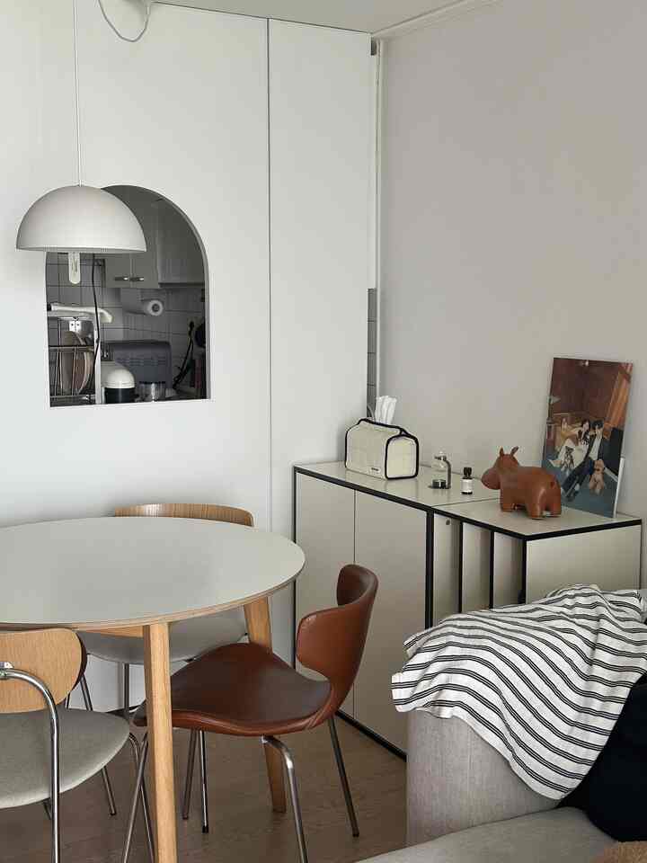 白とナチュラルブラウンのトーンが調和するリビング兼ダイニング、アーチ型間仕切りとラウンドダイニングテーブルが配置されたモダンな空間