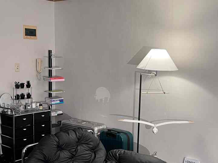 黒いレザーの椅子とクローム製のチェスト、白いシェードのフロアランプが置かれたミッドセンチュリーモダンの空間