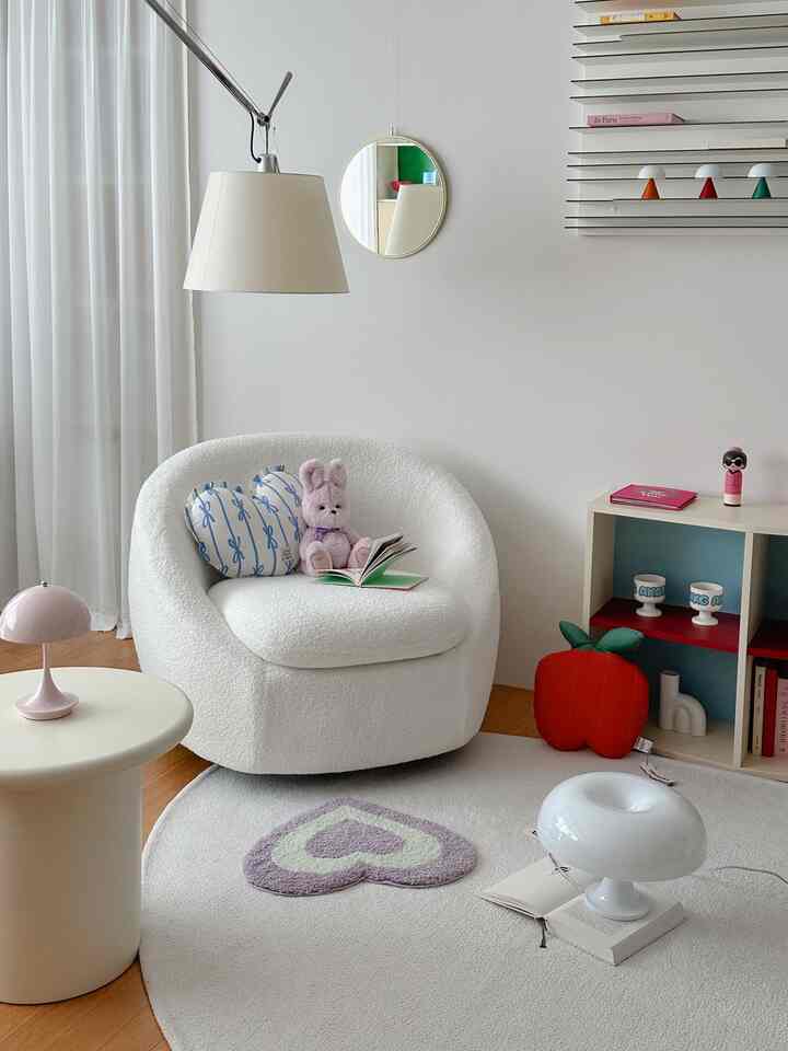 A white and beige toned kids' room featuring a simple single armchair and cute decorative items creating a cozy atmosphere