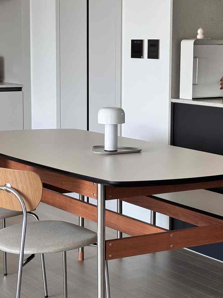 ホワイトとウッドトーンが調和したモダンなキッチンダイニング、中央にテーブルランプが配置された清潔感のあるインテリア