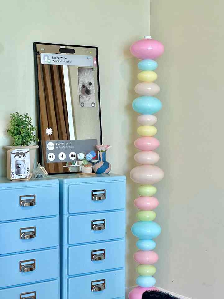 パステルカラーのリビング、ライトブルーのチェストとフェイスタイムミラーが配置された雰囲気のあるインテリア