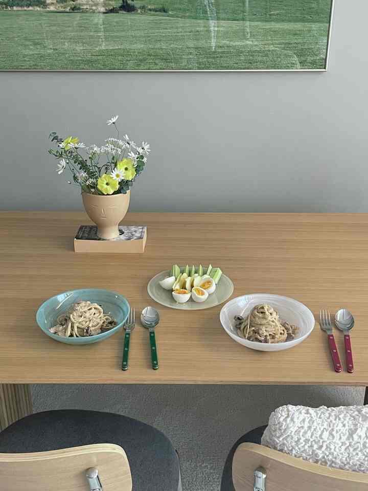 Beige-toned living room dining table featuring pastel-colored plates and cutlery set in a natural modern atmosphere