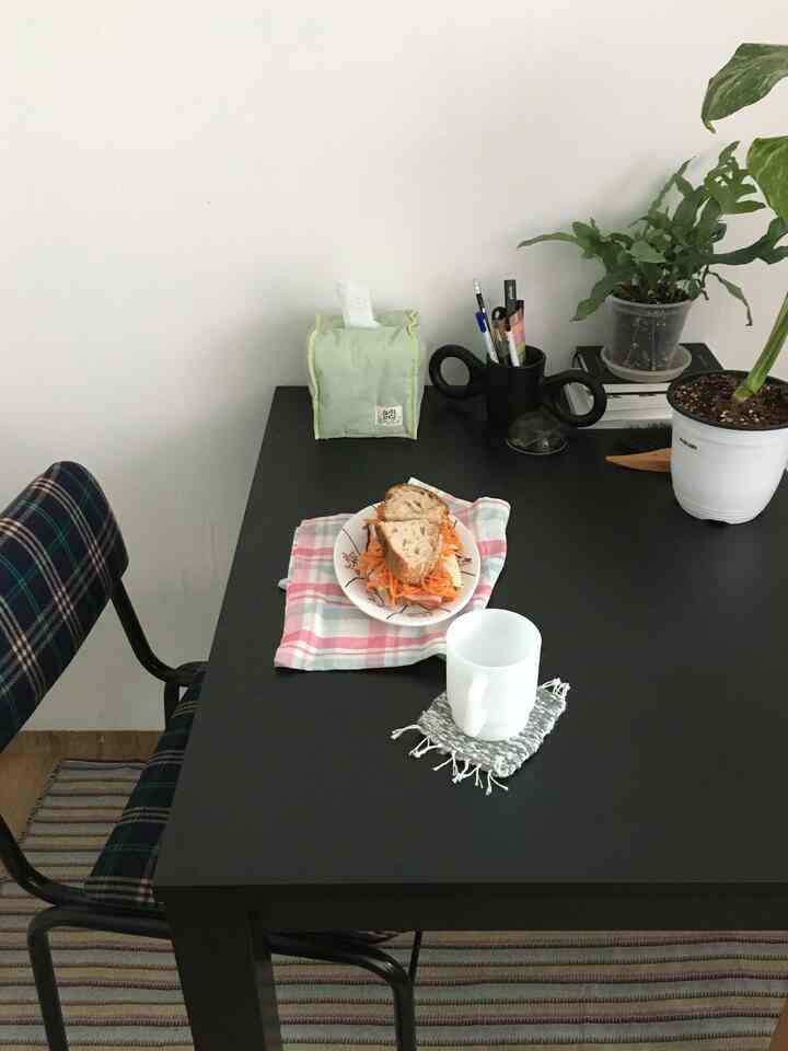 白と黒の色調のダイニングルーム、黒のダイニングテーブルと椅子、植物と食器が配置された雰囲気のある空間