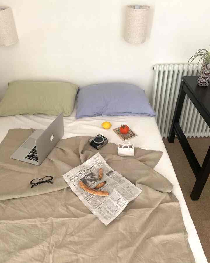 薄いベージュとアイボリーの色調の清潔感ある寝室、ノートパソコンと2つの枕を配したシンプルモダンな雰囲気