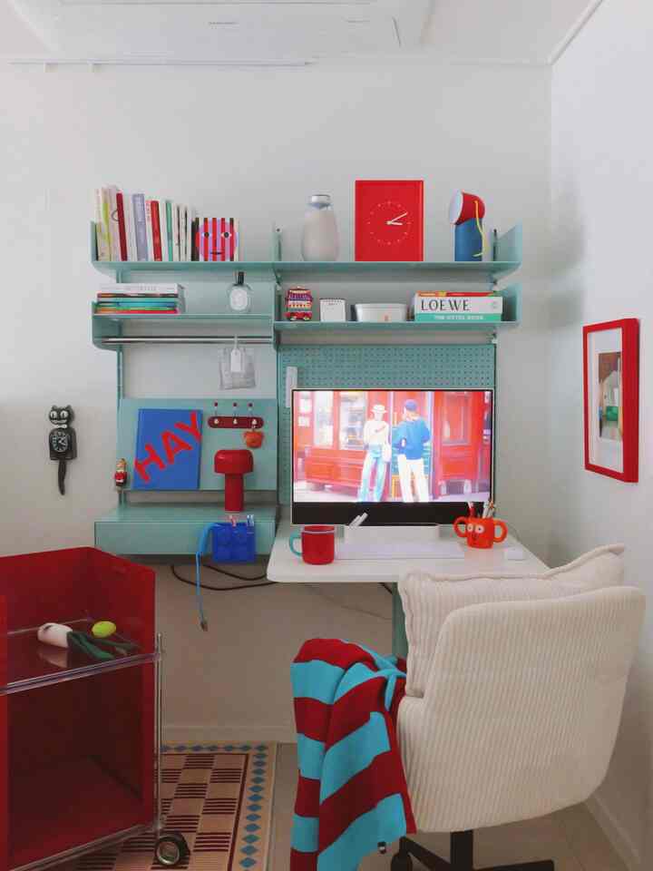 ミント色の棚と赤のアクセントが映えるホームオフィス、活気ある魅力的な作業空間のインテリア