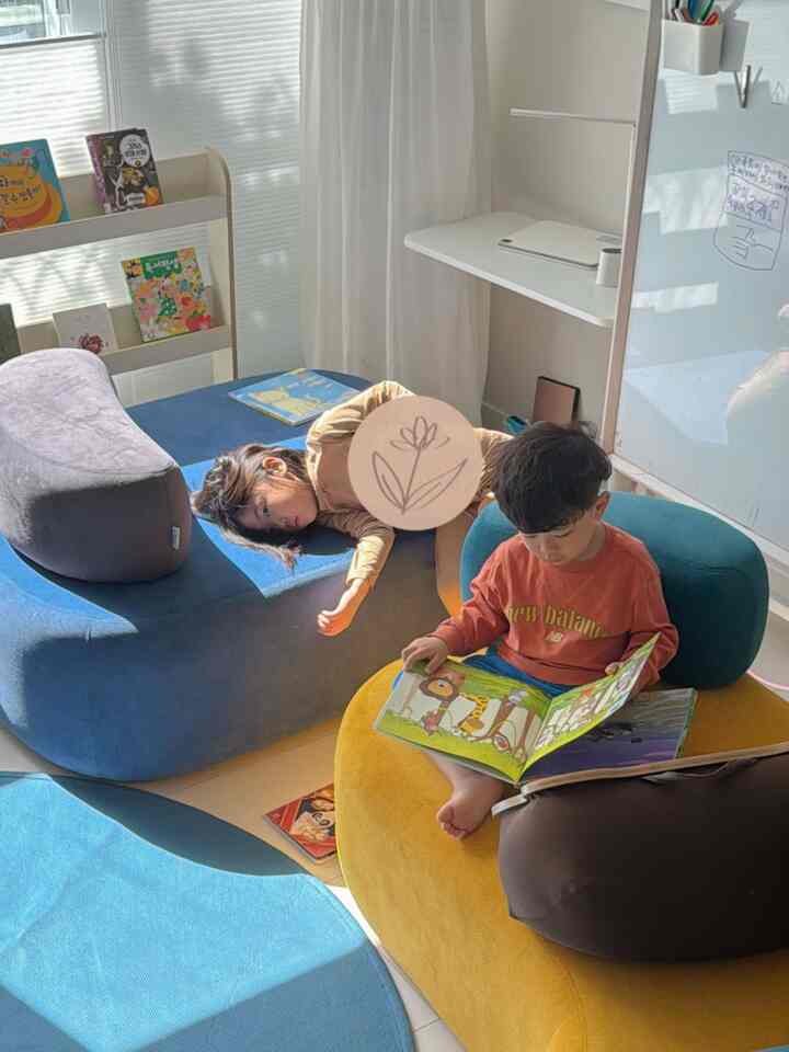 明るい色調の子供部屋、青と黄色のラグと本棚が配置された温かみのあるインテリア
