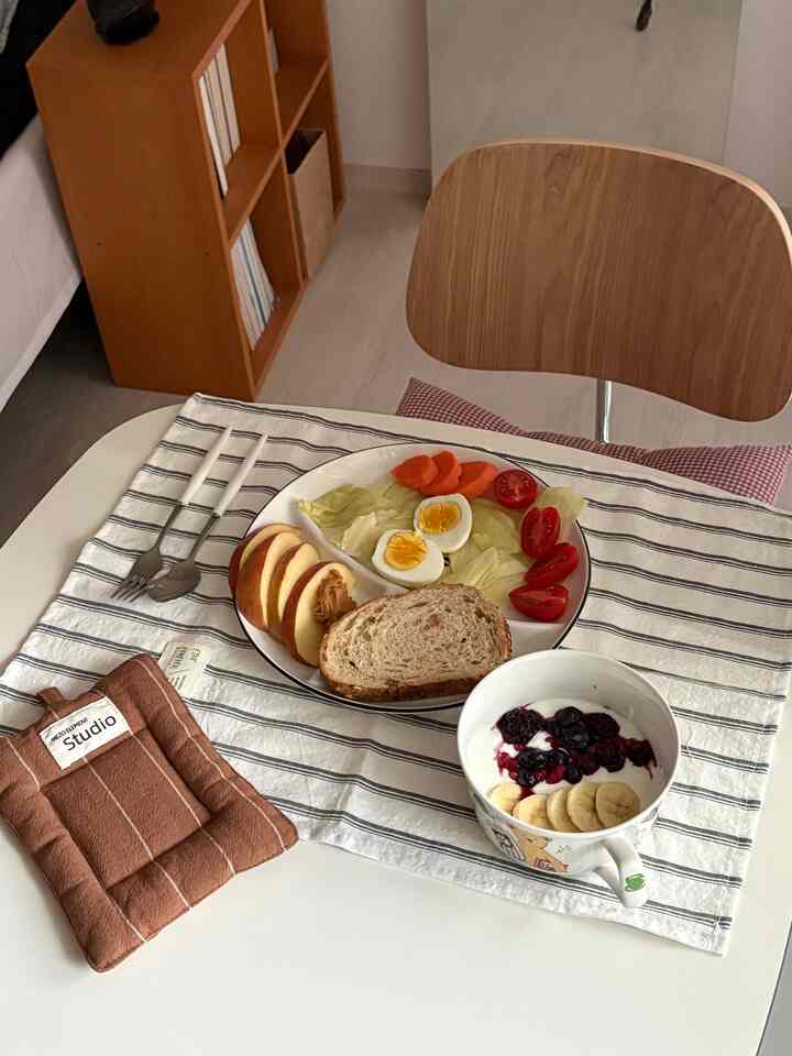 ナチュラルモダン調の小さなダイニングルーム、木目調の椅子と白いダイニングテーブルに軽い朝食が配置された落ち着いた空間