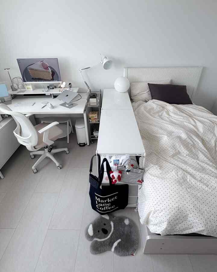 明るいホワイトトーンの寝室、白いベッドとデスクが配置され、モダンでシンプルなホームオフィスを兼ね備えた居心地の良い空間